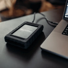 Load image into Gallery viewer, GLYPH Blackbox Plus beside a laptop in a mobile workspace